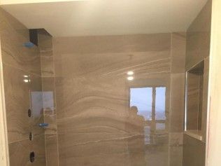 A tiled shower with a neutral color scheme and a window in the background.