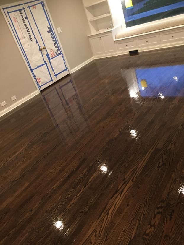 Shiny, dark wood floor in a room with a white built-in shelf and a door covered in blue paper.