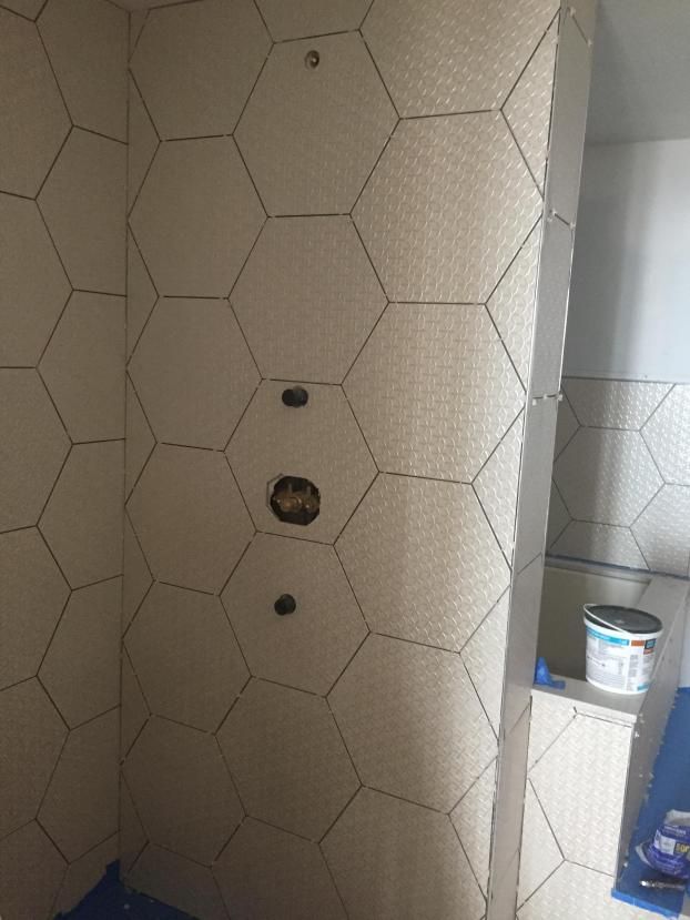 Bathroom walls with honeycomb-patterned tiles in neutral tones and dark grout.