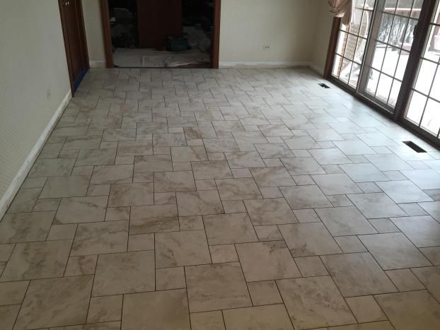 Light beige tile floor in a room, with a door, sliding glass door, and neutral-colored walls.