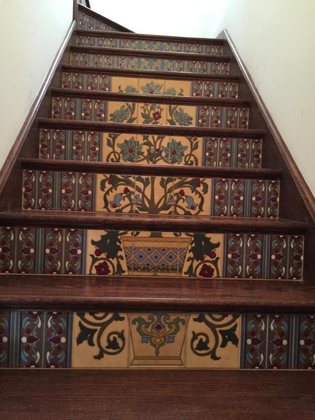 Wooden staircase with decorative floral tiles on each step.