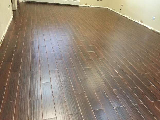 Dark brown, wood-look flooring installed in a room. The floor has a glossy finish and is mostly empty.