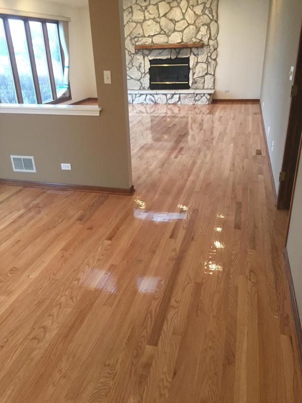 Hardwood floors in a room, with a stone fireplace in the background and natural light from a window.