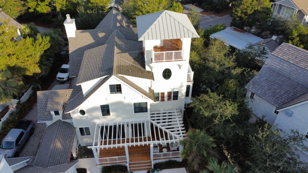 Aerial view of a white multi-level house with a tower and a gray roof
