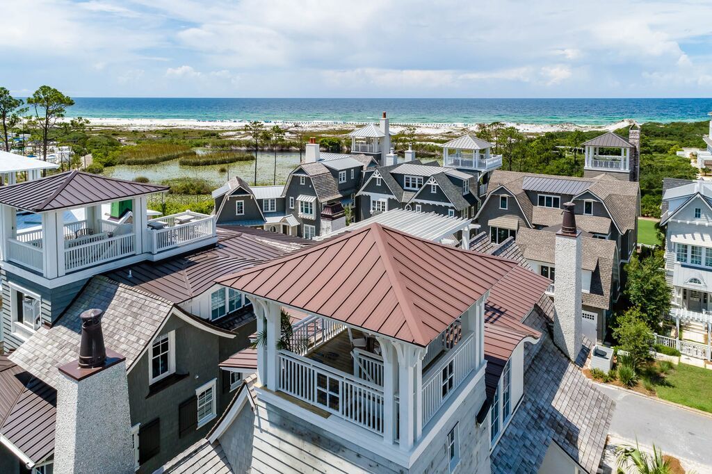 Aerial view of beachside homes with rooftop decks, facing the ocean.