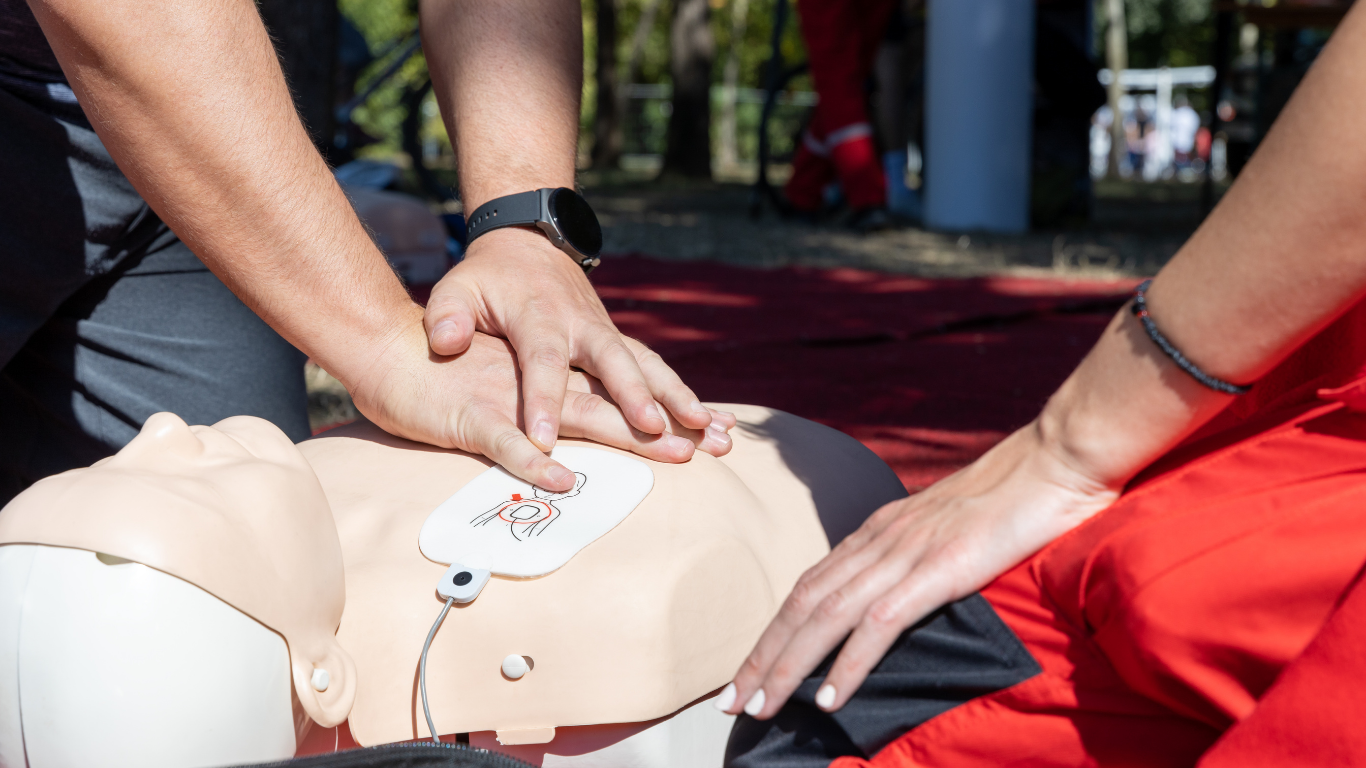 A man and a woman are practicing a defibrillator on a mannequin.