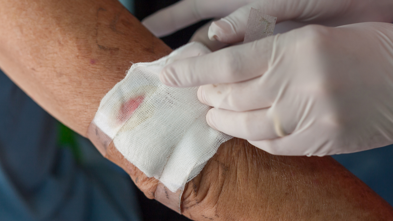 A person is applying a bandage to an older person 's wrist.