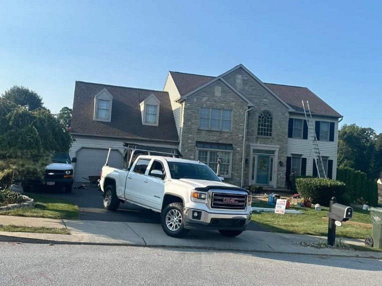 A white truck is parked in front of a large house.