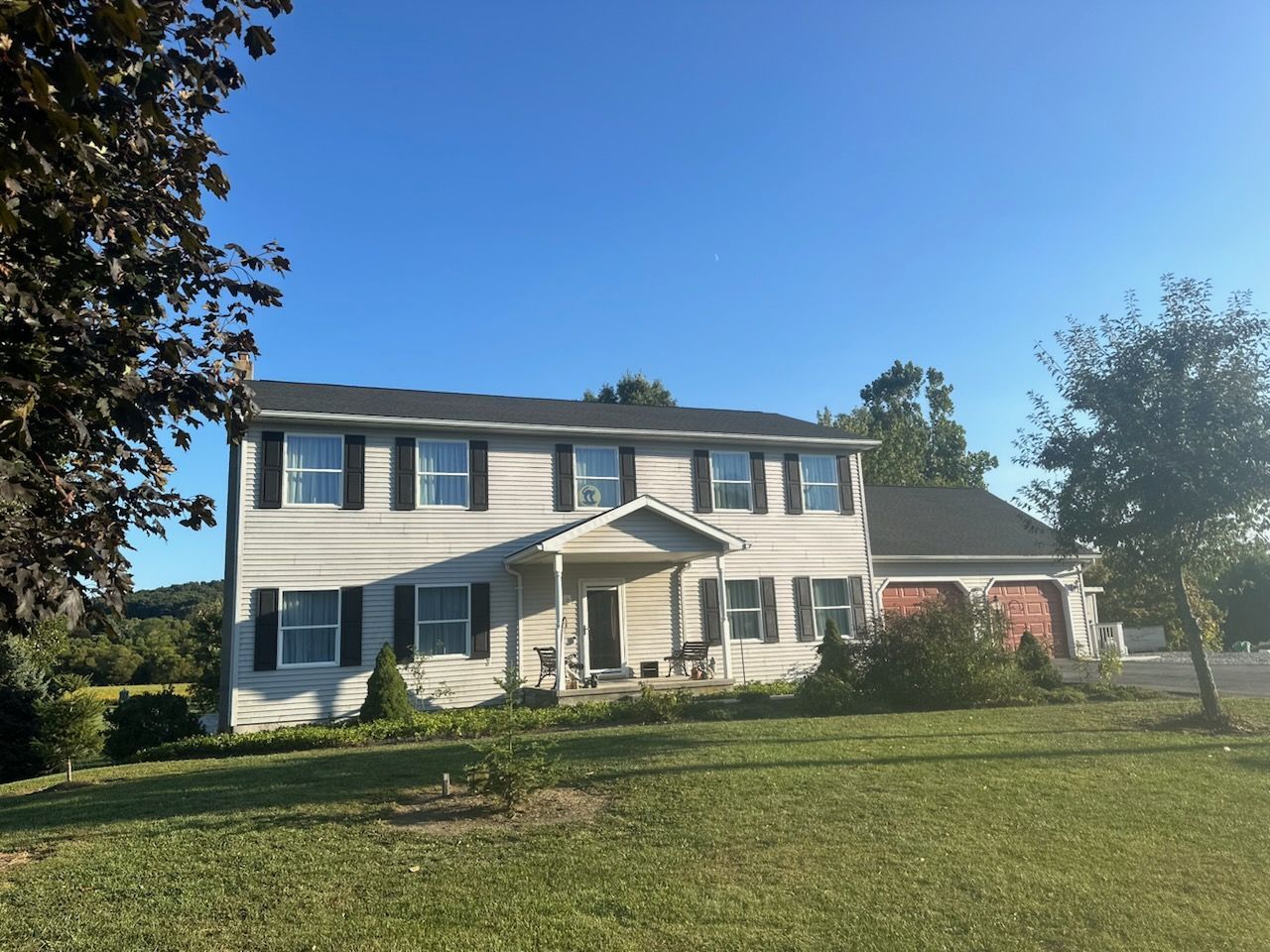 A large white house with black shutters and a blue sky in the background