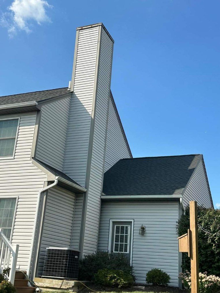 A white house with a chimney on the side of it