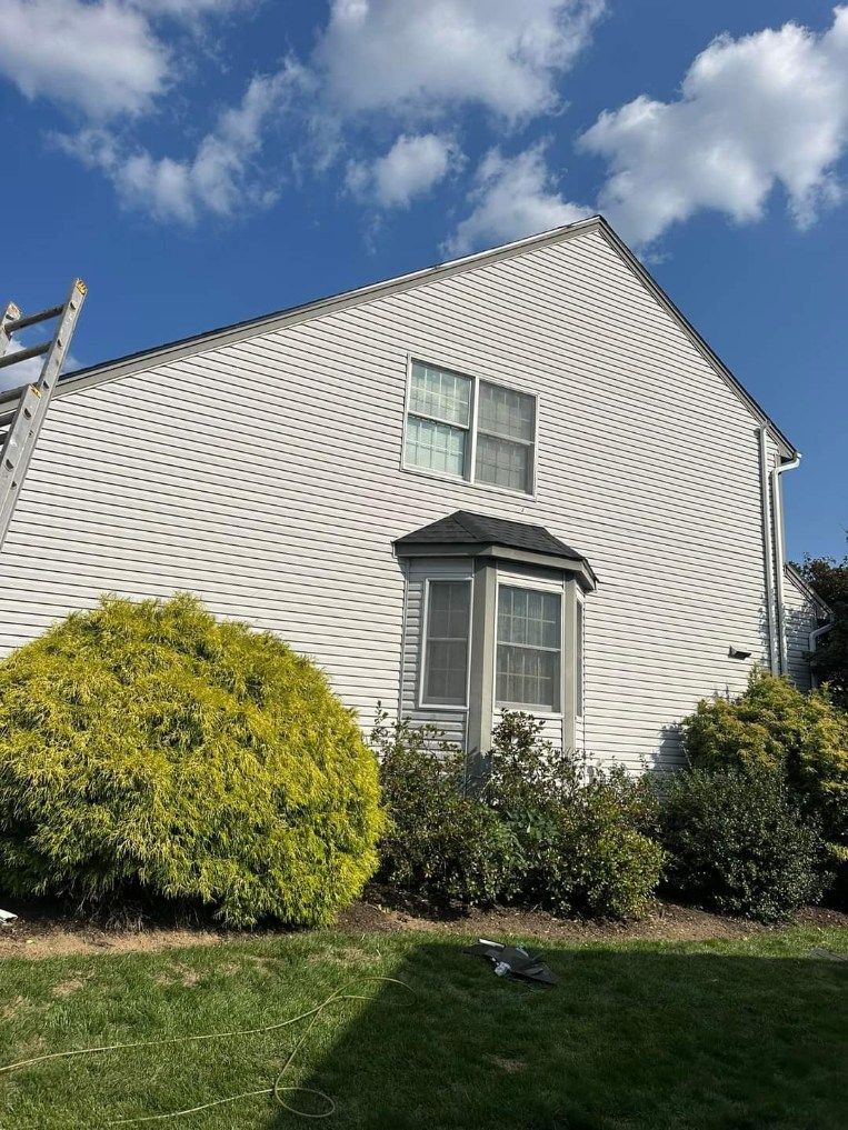 A white house with a lot of windows and bushes in front of it.