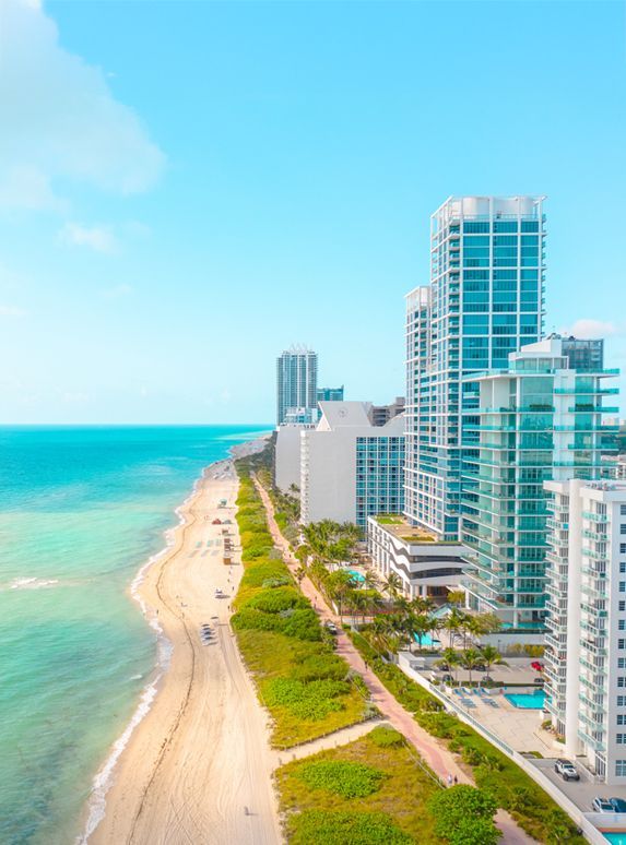 Beachfront buildings in Miami with turquoise ocean and blue sky.