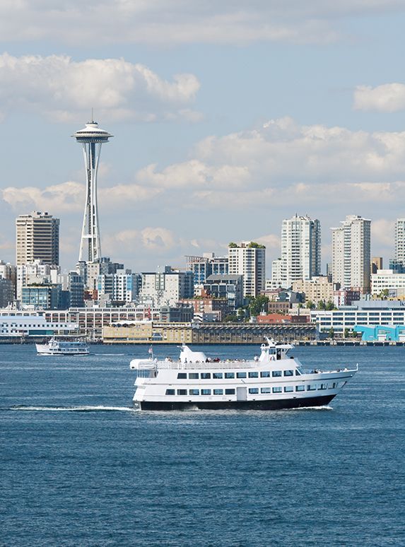 Seattle skyline with Space Needle, boat sailing on blue water.