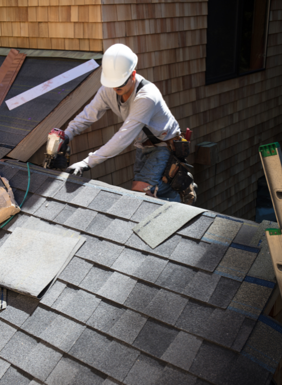A man wearing a hard hat is working on a roof