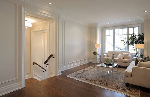 Living room with stairway, two beige sofas, window, and hardwood floors.