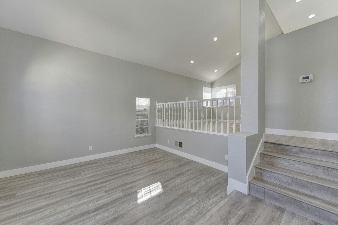 Empty interior with gray walls, wooden floors, and a staircase leading up.