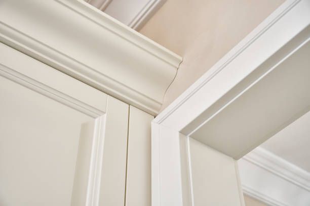 Close-up of white painted molding around a doorway and against a wall.