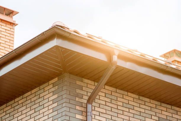 Brown gutters on a brick house, sunlight over the roof corner.