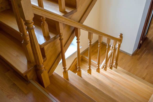 Wooden staircase with railing and balusters, seen from above.