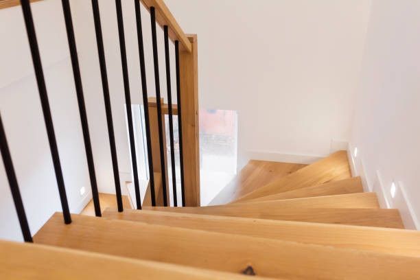 Wooden staircase with black railings, leading downward.