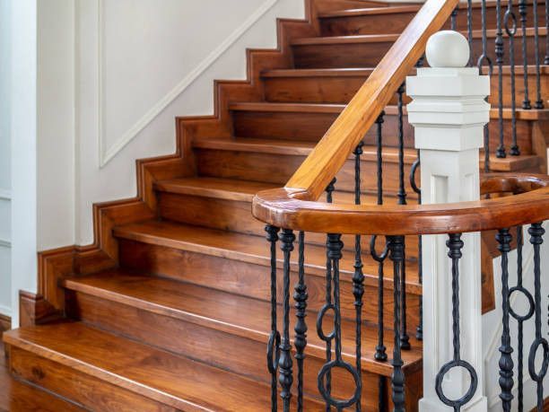 Wooden staircase with ornate iron balusters and a white support post.