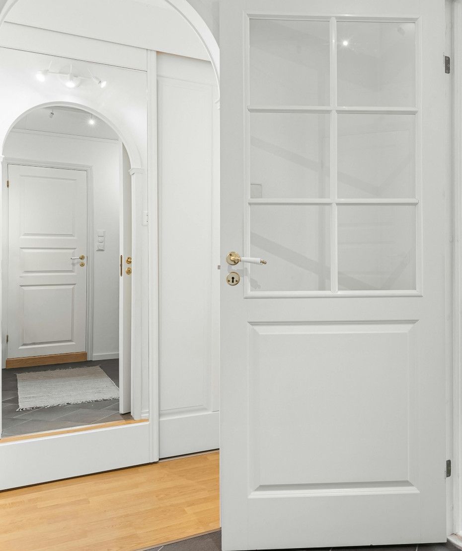 White doors in a hallway. One has glass panels, the other leads further in. Light wood floor.