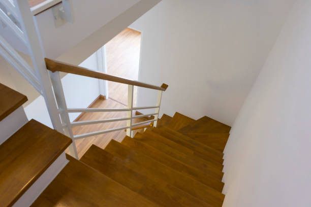 Wooden staircase with white railing descends into a hallway.
