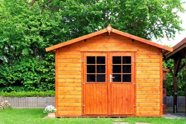 Wooden garden shed with double doors in a green yard.