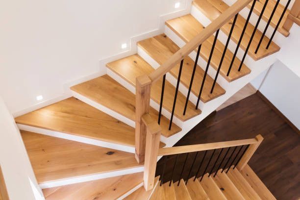 Wooden staircase with black metal railing, from overhead view.
