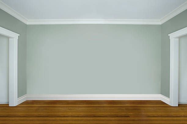 Empty room with pale green walls, white trim, and a wood floor.