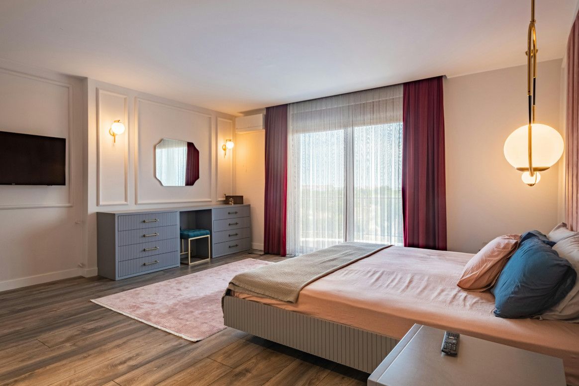 Bedroom with pink bed, gray dresser, and purple curtains.