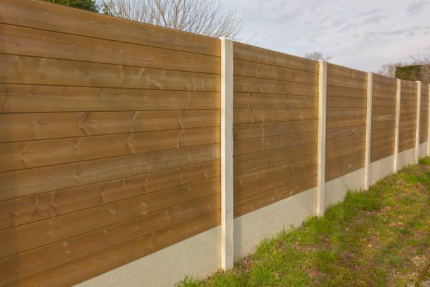 Wooden fence surrounding a grassy yard, under a bright sunny sky.