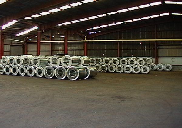 A warehouse filled with heaps of rolls of steel.