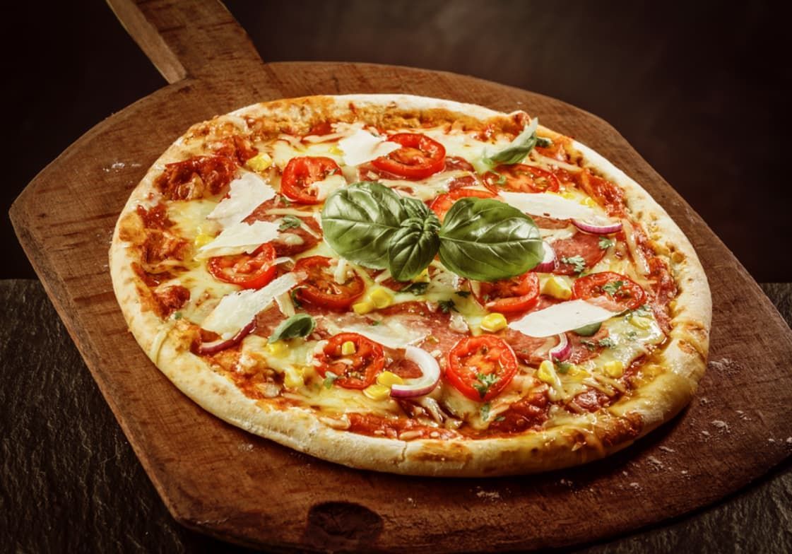A Pizza Is Sitting On A Wooden Cutting Board — Original North Australian in Bowen, QLD