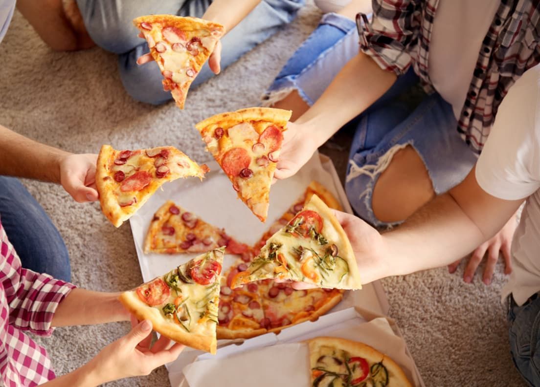 A Group Of People Are Sitting On The Floor Eating Pizza — Original North Australian in Bowen, QLD
