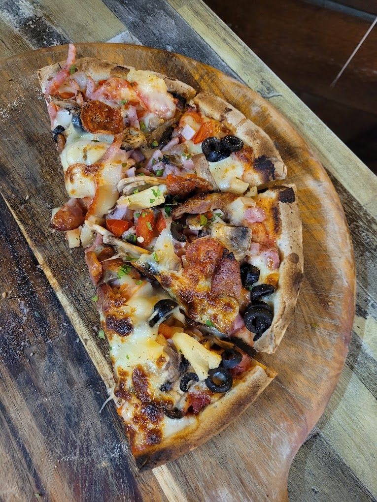 Two Pizzas Are Being Cooked In A Wood Fired Pizza Oven — Original North Australian in Bowen, QLD