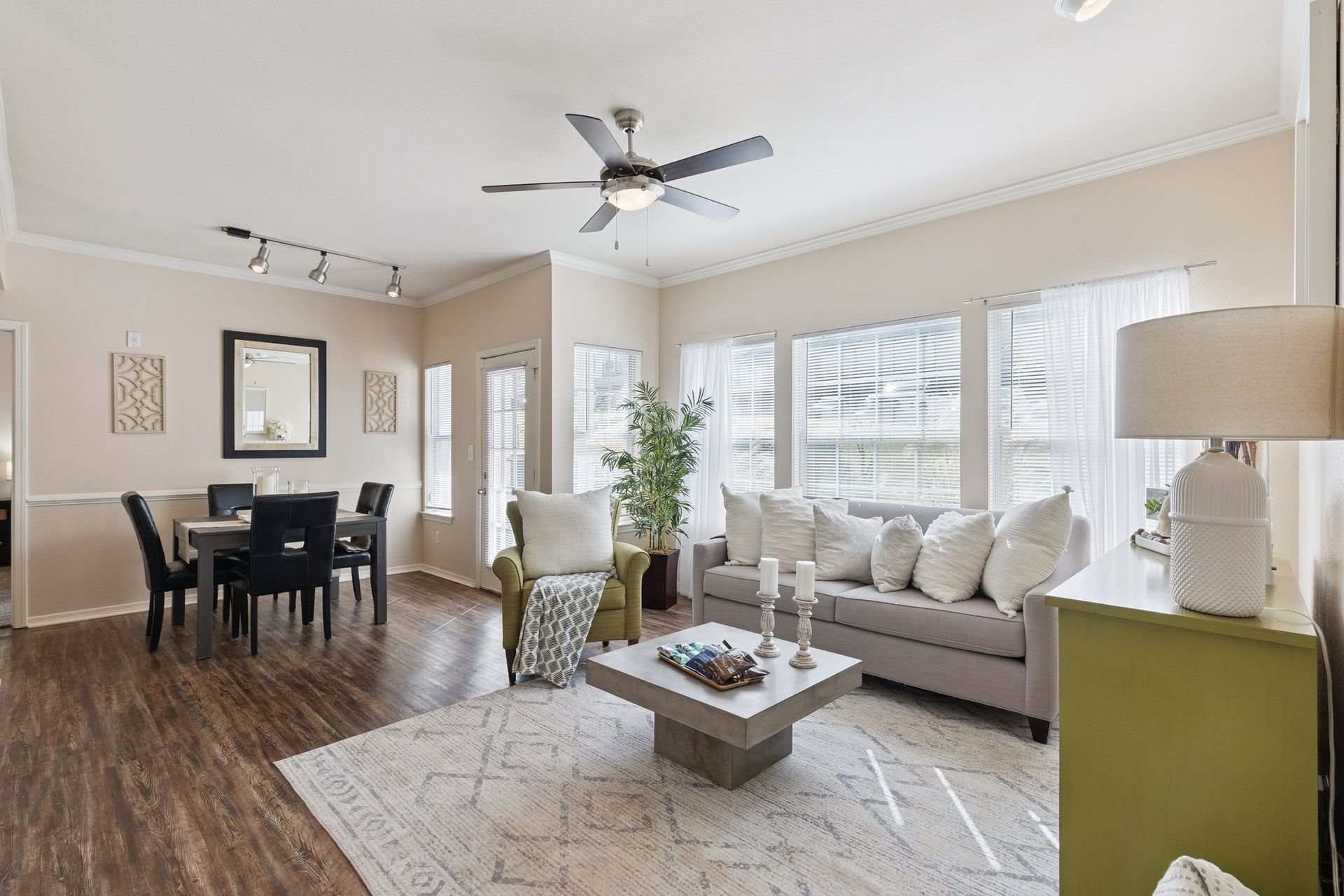Living room with dining area. Gray sofa, green accent cabinet, square coffee table, and large windows.