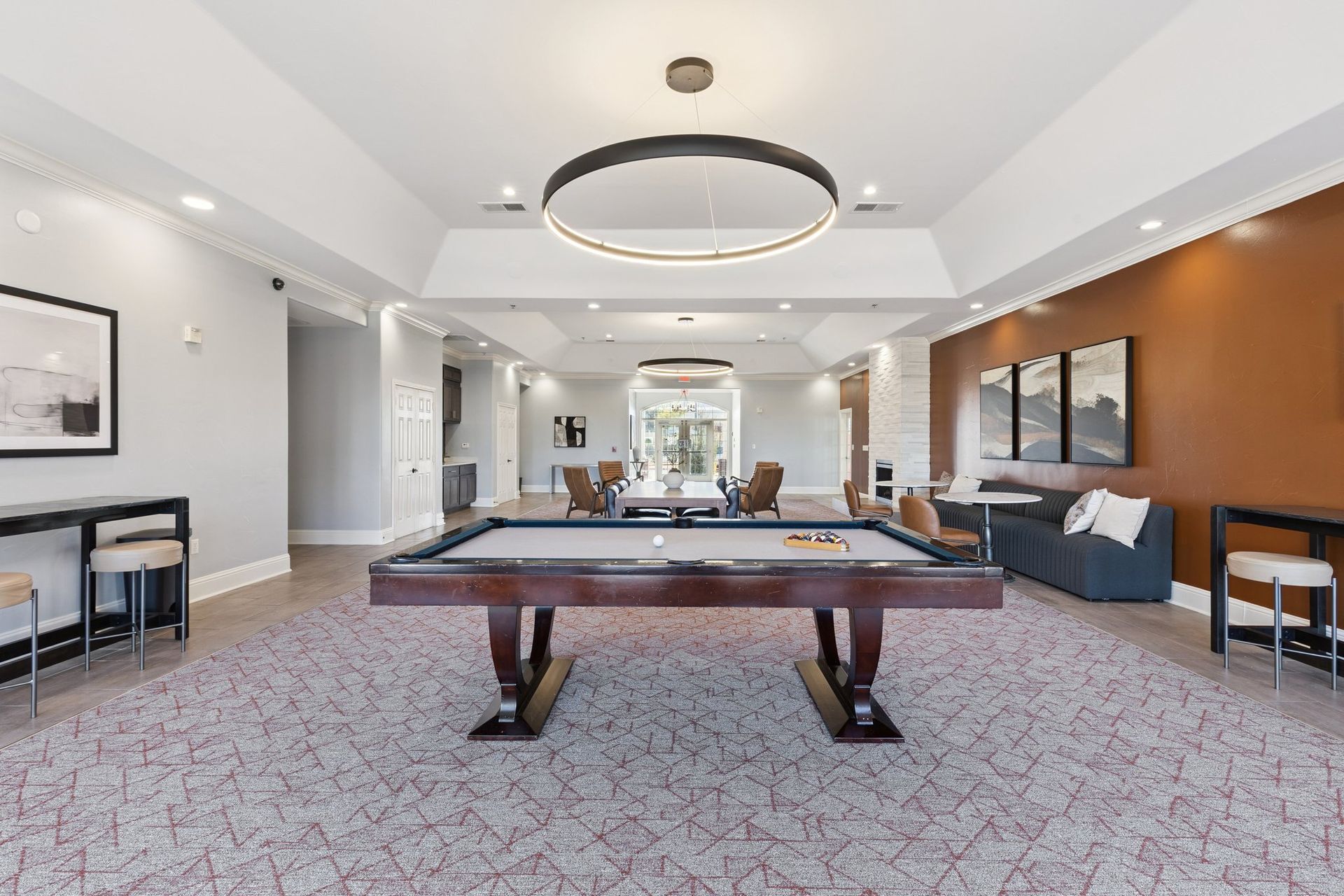 Pool table in a spacious room with seating areas and a decorative circular light fixture.