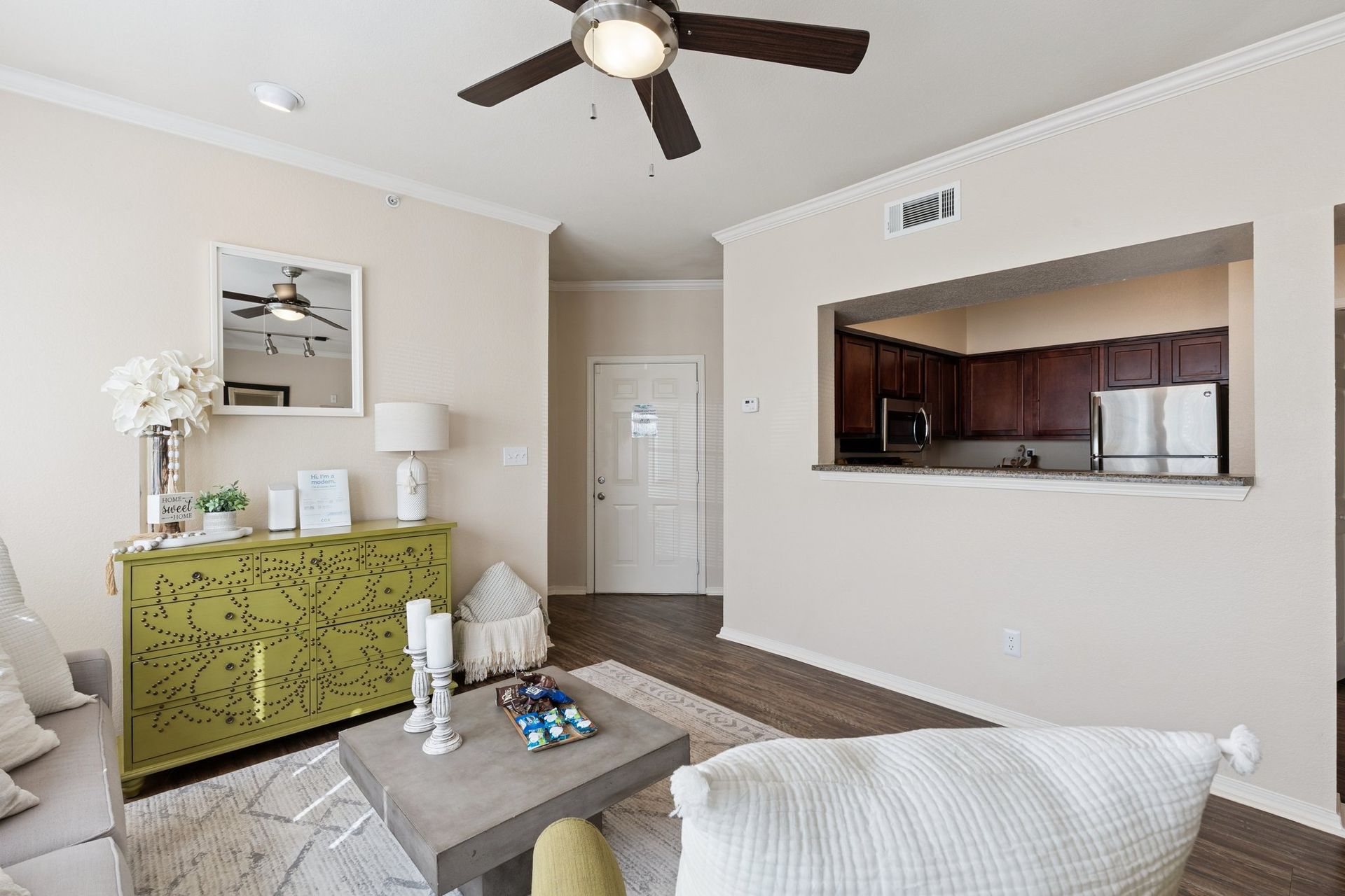 Living room with a kitchen pass-through, light walls, and a green cabinet with decorations.
