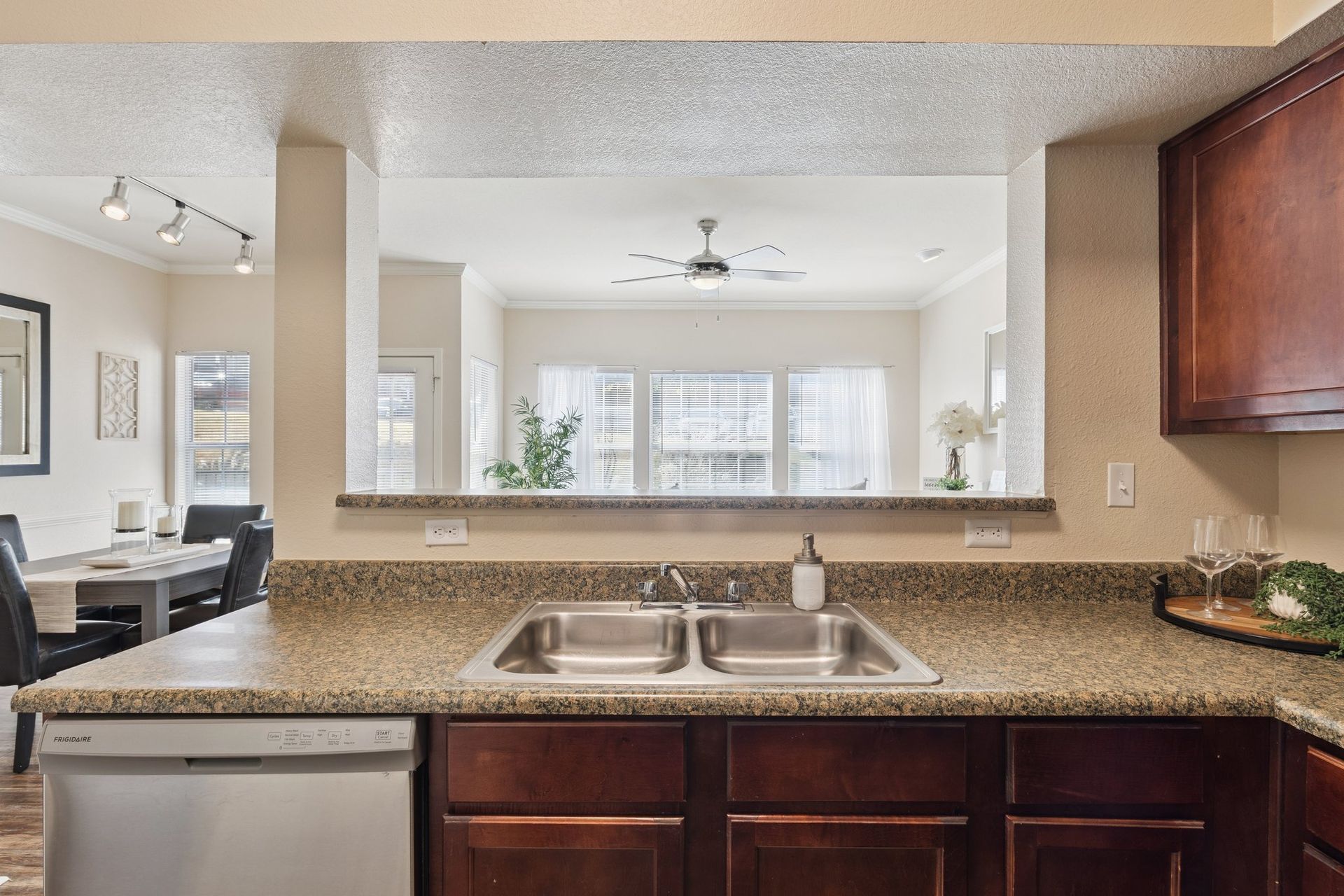 Kitchen with countertop, sink, and view into the living room. Brown cabinets and granite counter.