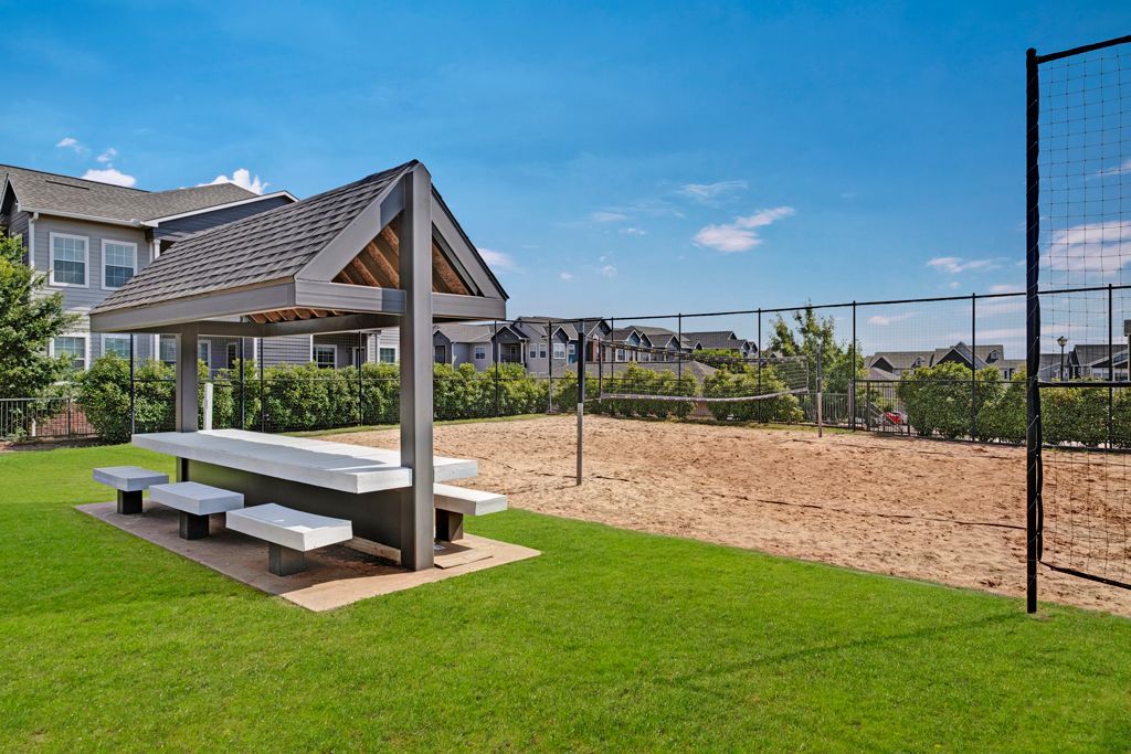 There is a picnic table in the middle of the grass next to a volleyball net.