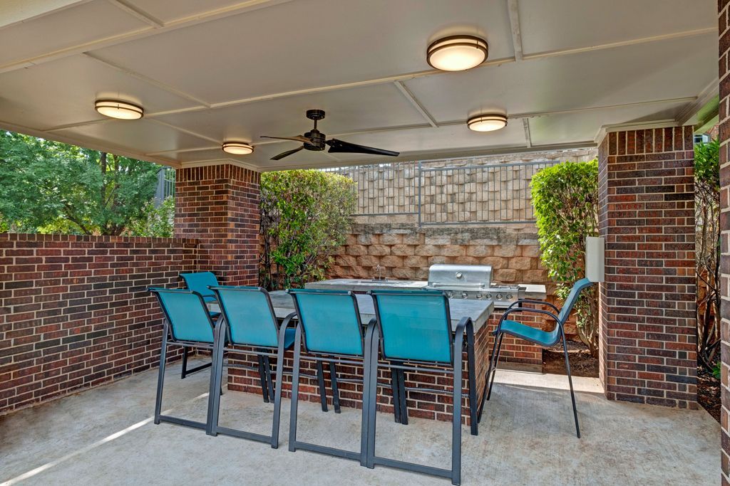 A patio with a table and chairs and a ceiling fan.
