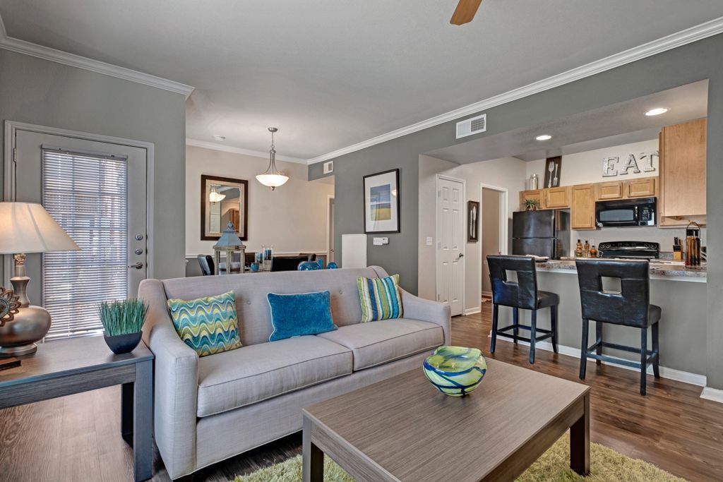 A living room with a couch , coffee table , chairs and a ceiling fan.