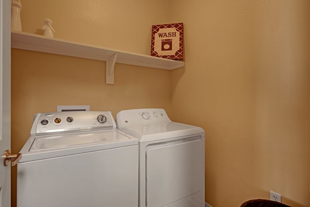 A laundry room with a washer and dryer and a sign on the wall.