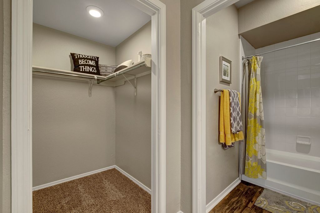 A walk in closet and a bathroom in a house.