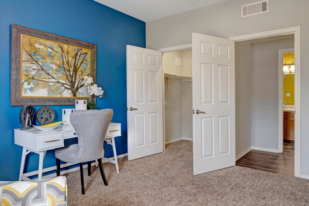 A bedroom with a desk , chair , and closet.