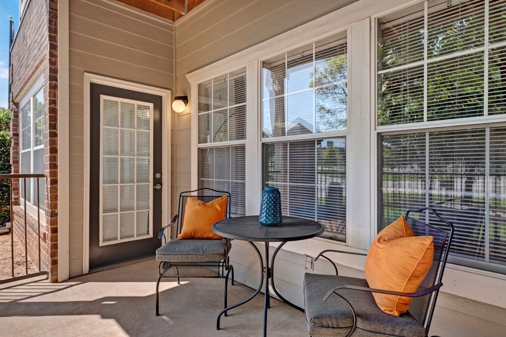 There is a table and chairs on the porch of a house.