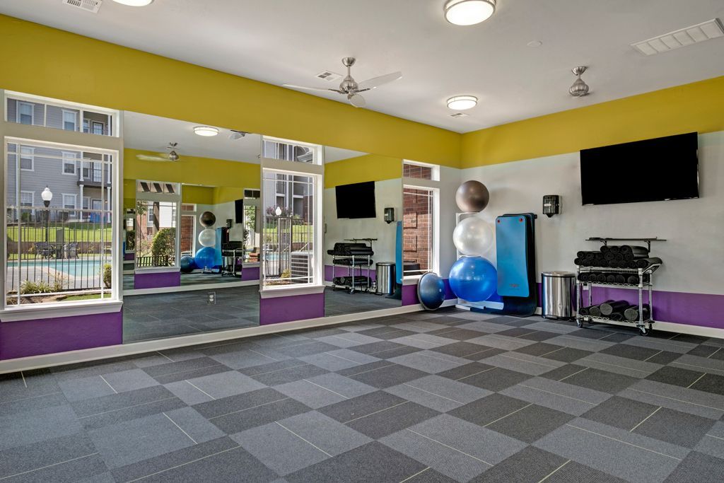 A large room with a lot of mirrors and exercise equipment in a gym.