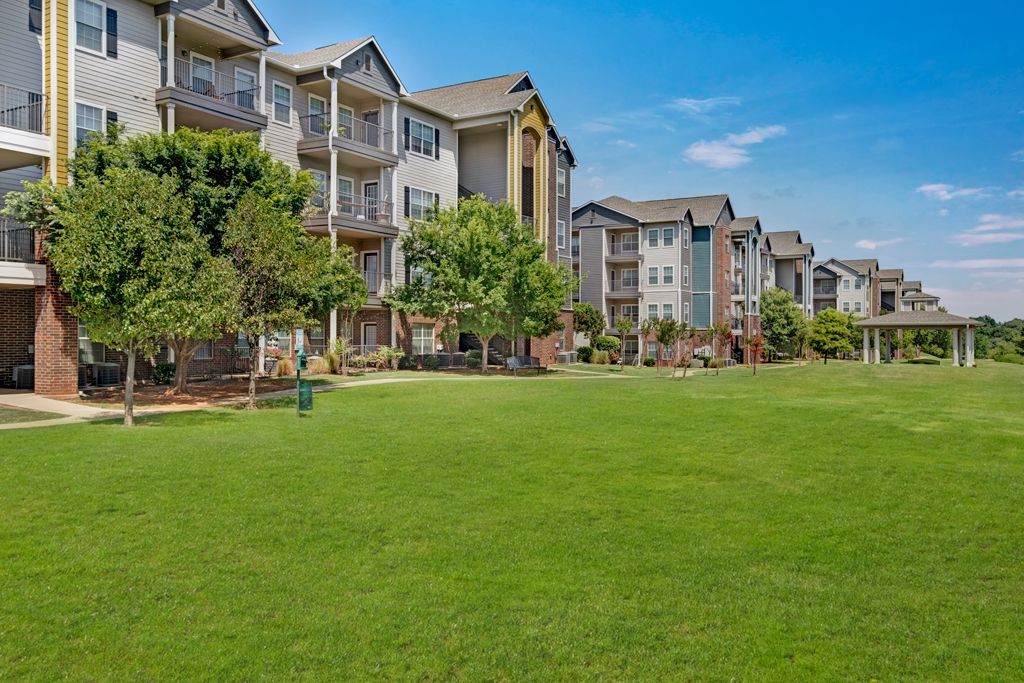 A large lawn in front of a row of apartment buildings.