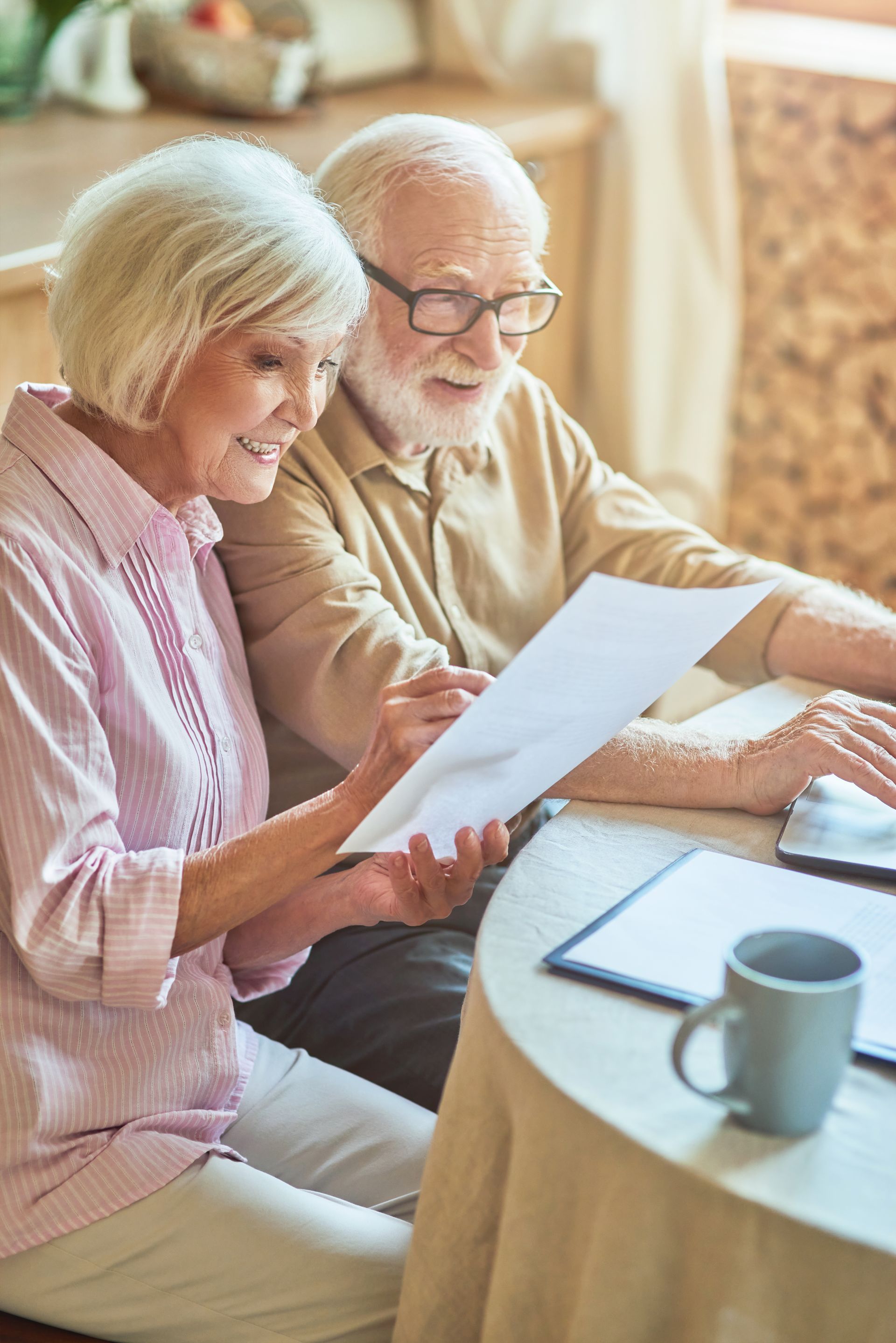Older couple reviewing paperwork together at a table, smiling.